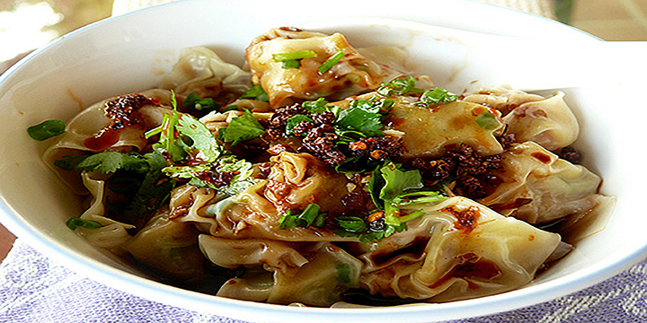 Bowl of spcicy Chinese dumplings with chilli, herbs and spices