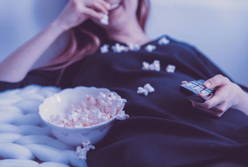 woman eating popcorn on couch