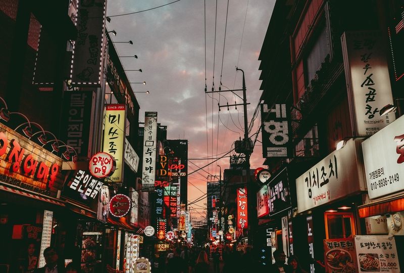 Neon signs in Korean against a pink-sky