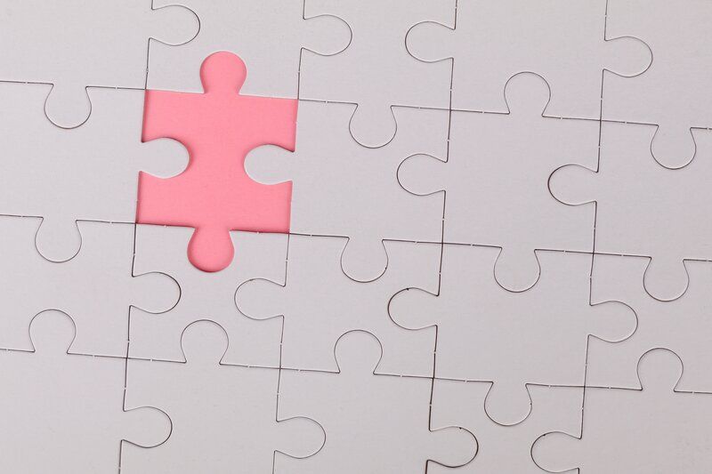 a pink puzzle piece stands out from the rest