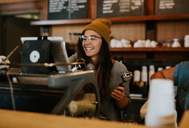 barista smiling as she makes coffee