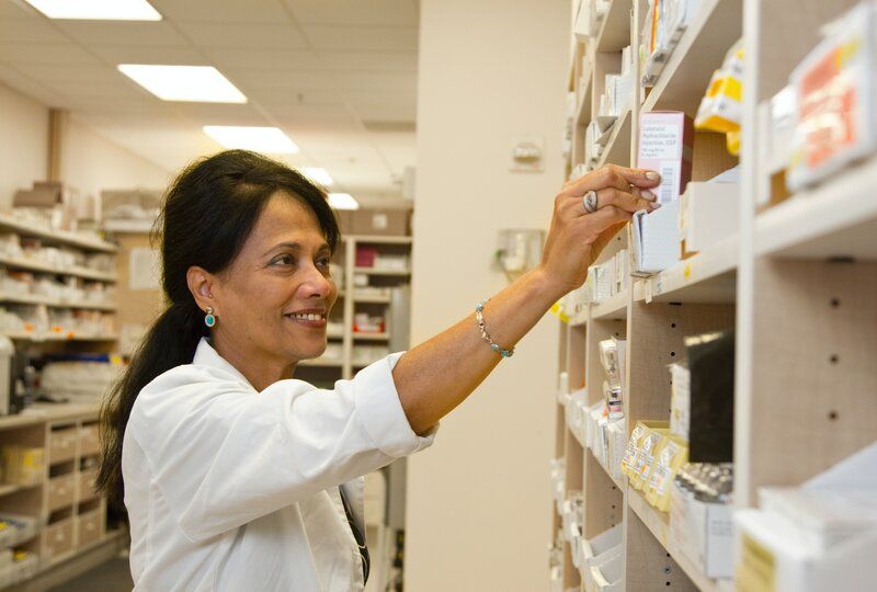 a smiling pharmacist restocking shelves