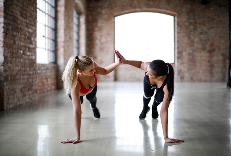 two women high-fiving as they perform a plank