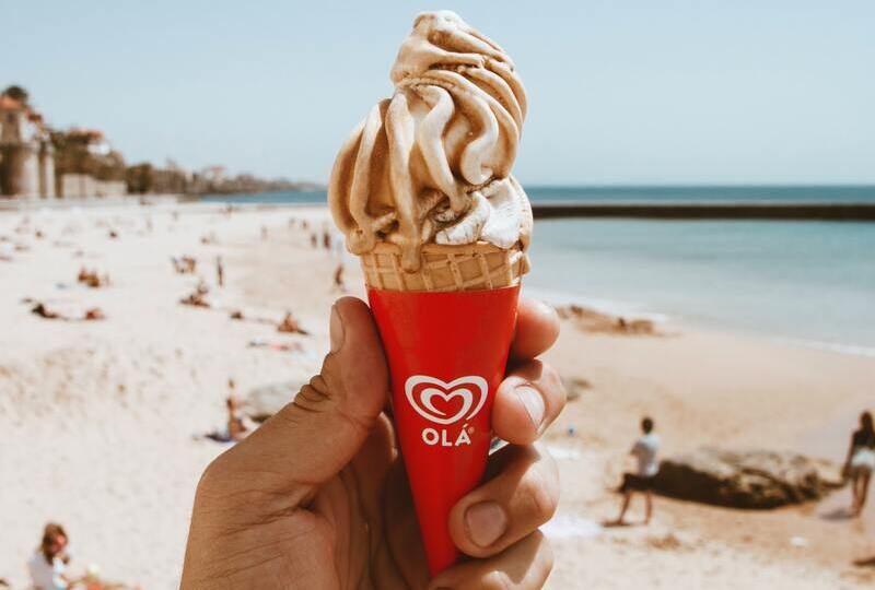 holding up ice cream that says ola on a beach