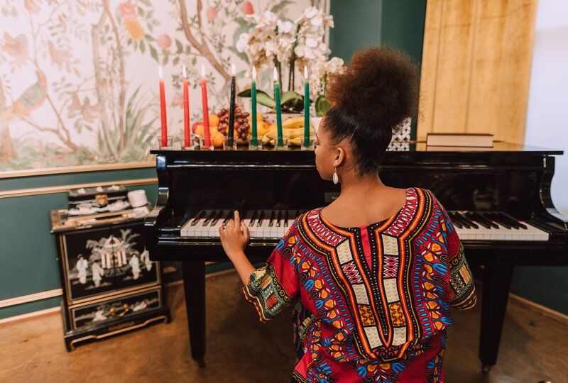a woman playing the piano next to kwanzaa candles