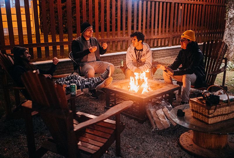 A group of friends are talking beside a fire pit