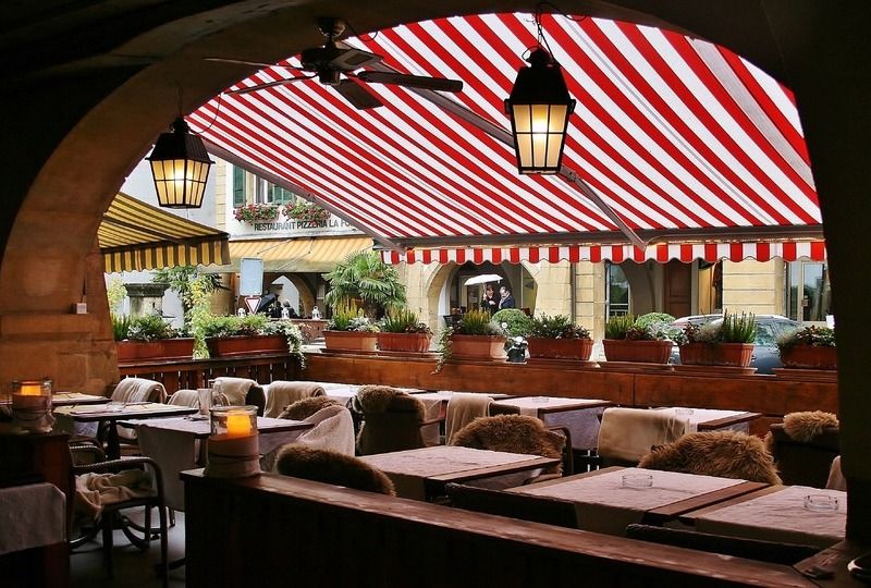 The outside section of a restaurant under a white and red striped awning