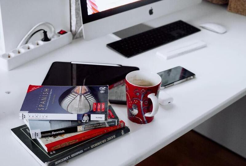 Stack of Spanish books on a desk with a coffee