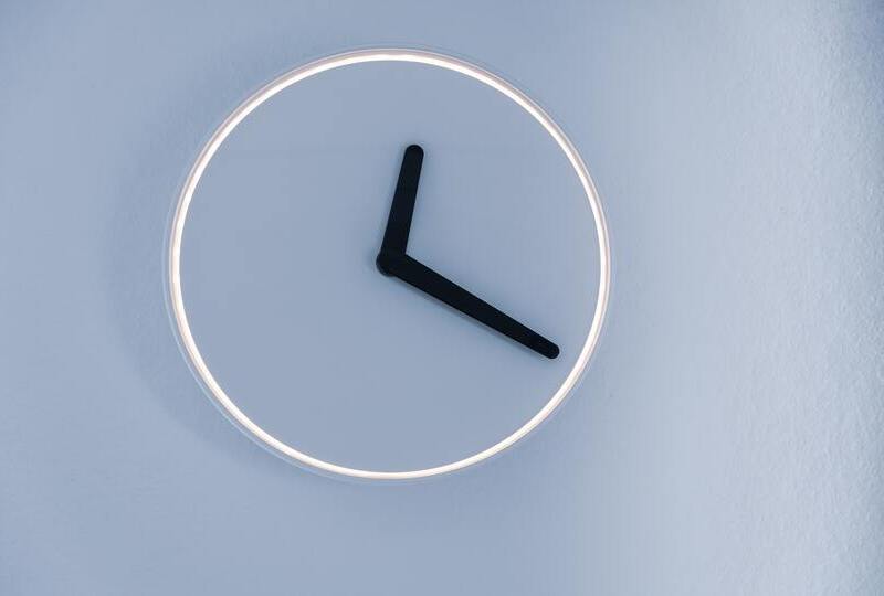 A blue wall with a simple clock without numbers