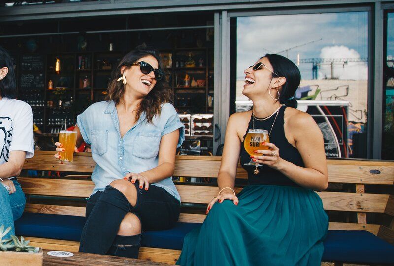 two women practicing english holding beers