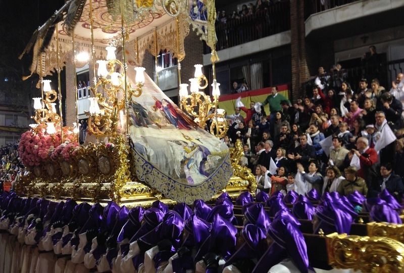 A large procession as people dressed in purple carry a religious icon on their shoulders