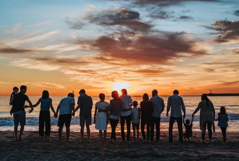A large family holding hands on the beach during a sunset