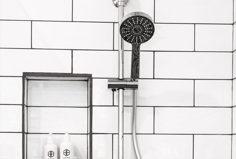 A shower head in a white tiled shower