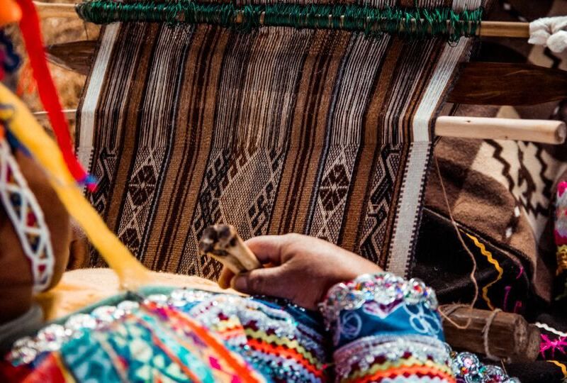 A close-up of a woman weaving a traditional Latin American textile