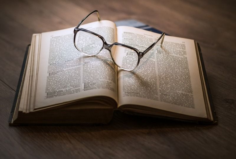 An open book with a pair of glasses resting on top