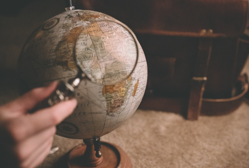 Someone holding a magnifying glass in front of a globe