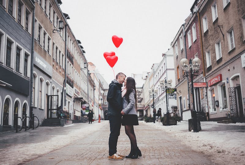 Couple kissing in street with heart balloons