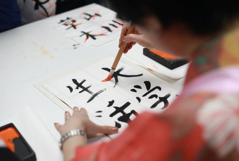 A person holding brush drawing Japanese Characters
