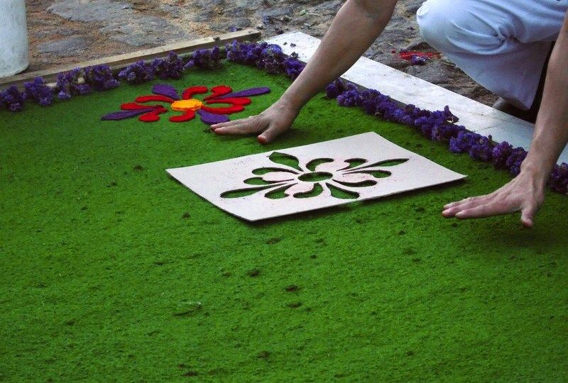 Hands working on a carpet made of flower petals