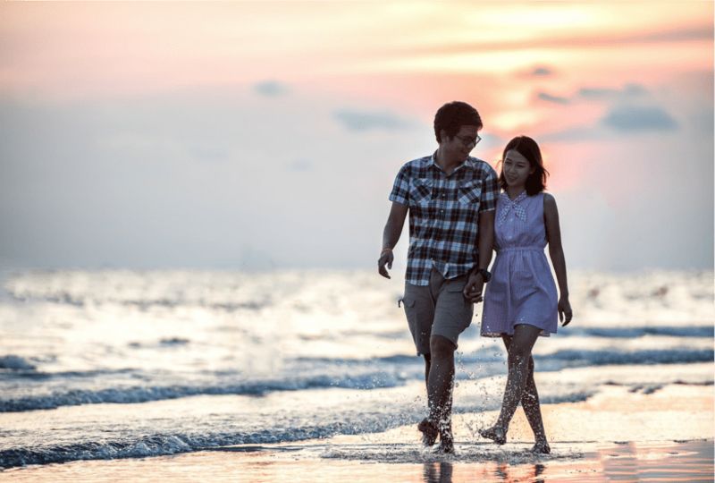 A loving couple is walking on beach during sunset