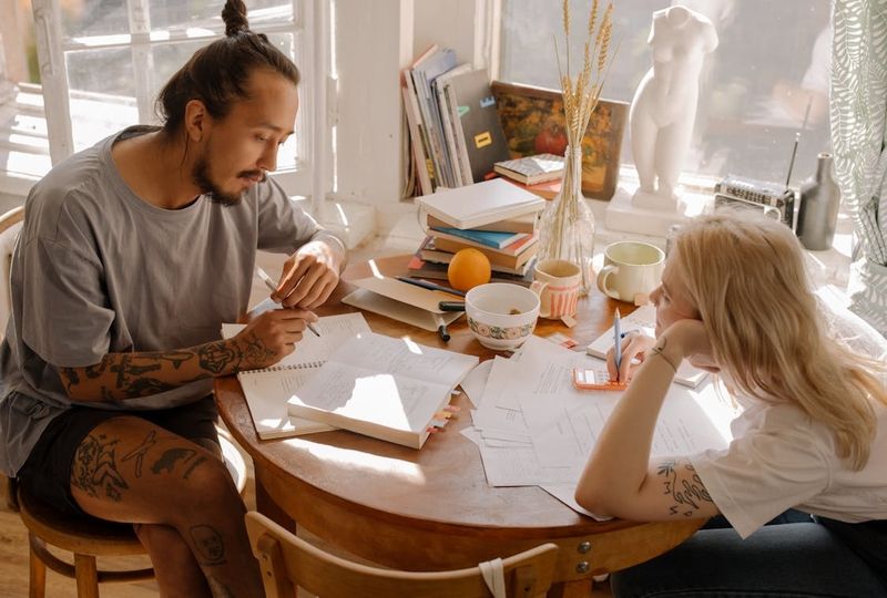 woman and man sitting in front of the table in a sunny room learning english