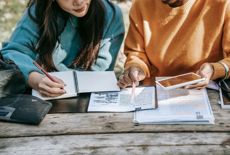 woman in blue shirt and a woman in orange shirt learn English together in nature