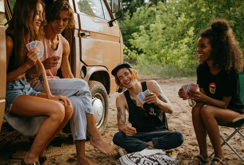 friends playing board games in front of the van in nature