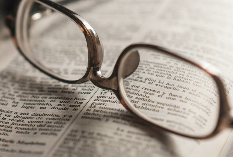 An open book with glasses resting on it