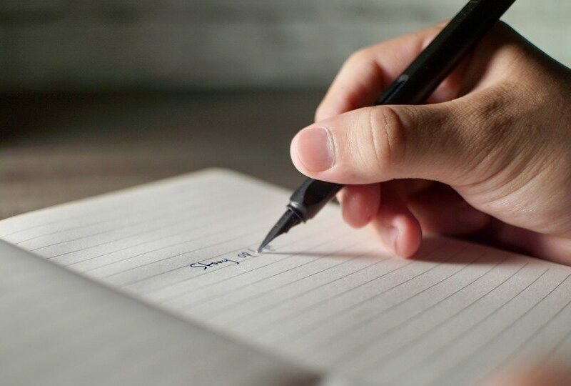 A hand writing in a notebook