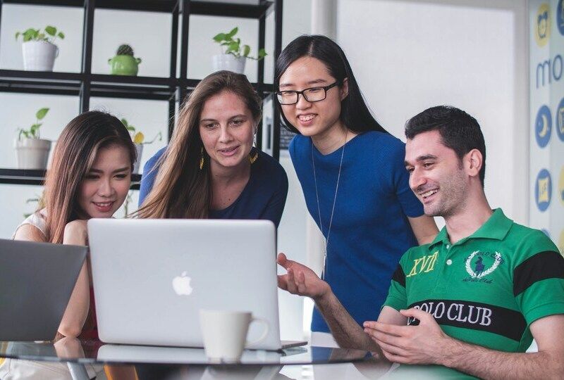 A group of colleagues gathered around a computer screen