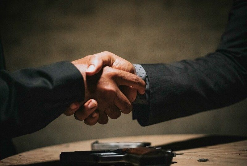 A closeup of two men in suits giving a business handshake