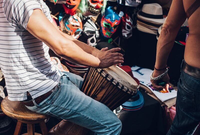 A young man playing a drum in a festival setting
